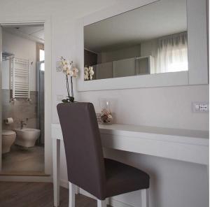 a bathroom with a desk with a chair and a mirror at Hotel Ardea in Riccione