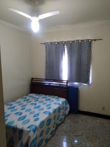 um pequeno quarto com uma cama e uma janela em Apartamento charmoso em Saquarema