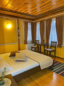 a bedroom with a bed and two chairs and windows at Guest rooms Colorit in Koprivshtitsa
