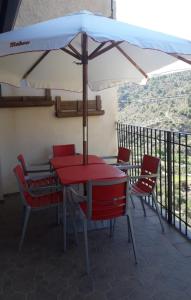 una mesa y sillas con una sombrilla en el balcón en Casa Rural Elena, en Ayna