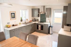 a kitchen with gray cabinets and a table and a kitchen with a stove at RiverTree House in Llangollen