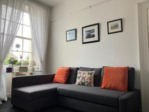 a living room with a gray couch with orange pillows at Buttercup Cottage in Dundrum