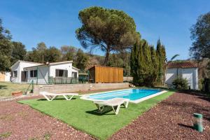 a swimming pool with two chairs and a table at Casa con piscina cerca de Girona in Girona