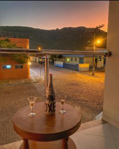 a table with a bottle and two glasses on it at Pousada Vista Bela in Mucugê