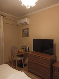 ein Schlafzimmer mit einem TV auf einer Kommode und einem Schreibtisch mit einem TV auf in der Unterkunft Home Sweet Rental in Tirana