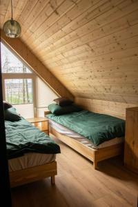 2 camas en una habitación con techo de madera en STOLEMOWE Wzgórze Domek Leśnika, en Perlino