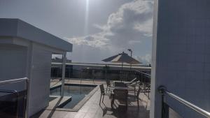 eine Terrasse mit einem Tisch und einem Sonnenschirm auf dem Balkon in der Unterkunft Lindo apartamento, ao lado do Shopping Partage Nova Betânia Ed WHB in Mossoró
