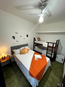 a bedroom with a bed with an orange blanket on it at Pousada Tribo Ubatuba in Ubatuba