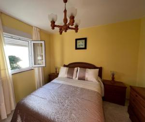 1 dormitorio con cama, ventana y lámpara de araña en Apartamento Playa de Lires, en Cee