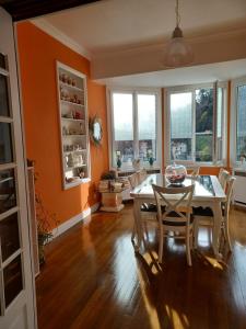 a dining room with orange walls and a table and chairs at Ma promesse in Vals-les-Bains