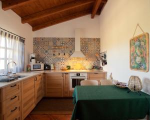 una cocina con armarios de madera y una mesa verde en Cosy Farmhouse Quinta da Eira 140 years old en Loulé