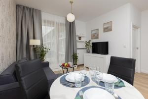 comedor con mesa blanca y sillas negras en Oś Królewska - Comfortable Apartment in Wilanów en Varsovia