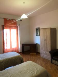 1 dormitorio con 2 camas, escritorio y ventana en Casa Alighieri, en Montalto Uffugo