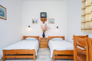 2 Betten in einem Zimmer mit einem TV an der Wand in der Unterkunft Golden Beach Glyfada Apartments in Kastraki Naxos