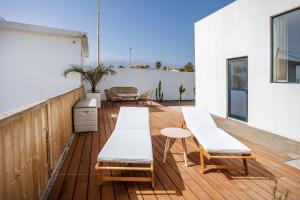 una terraza de madera con sillas blancas y una mesa en Villa Arizona - 3-bedroom house by the sea en El Médano