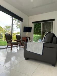 uma sala de estar com um sofá, cadeiras e janelas em Casa campestre Buenavista - La Mesa em La Mesa