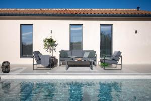 een patio met 2 stoelen en een tafel naast een zwembad bij Villa TonKa with jacuzzi sauna and private pool in Labin
