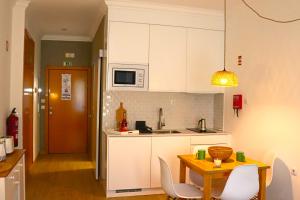 a kitchen with white cabinets and a table and chairs at Sunrise Apartmento Ribeira d'Ilhas Ericeira in Ericeira