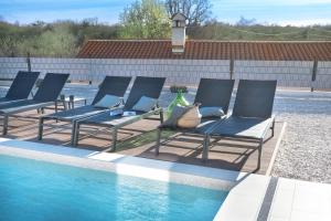 un grupo de sillas sentadas junto a una piscina en Villa TonKa with jacuzzi sauna and private pool en Labin