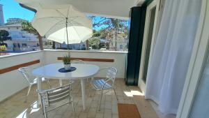 a white table and chairs on a balcony with an umbrella at Villa Barbara Fra i Pini in Lignano Sabbiadoro
