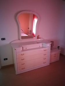 - une commode blanche avec un miroir au-dessus dans l'établissement Appartamento mare, à Siderno Marina