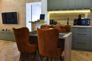 une cuisine avec une table et des chaises ainsi qu'une télévision dans l'établissement Duga Apartmani 1, à Subotica