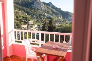 a table and chairs on a balcony with a mountain view at Pink Palace Beach Resort in Agios Gordios