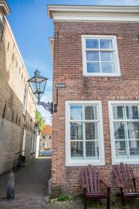 a brick building with two chairs and a window at Pension B&B Pluk in Zierikzee