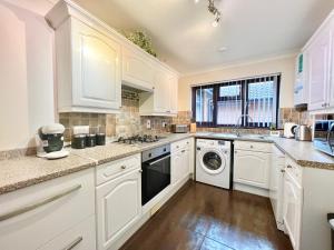 uma cozinha com armários brancos e uma máquina de lavar e secar roupa em 3 Bedroom house - Sandown em Sandown