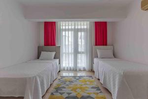 two beds in a room with red curtains at Güneş Villa in Antalya