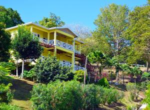 a yellow house on a hill with trees and bushes at Seascape Villa 3BR with Stunning Caribbean Sea View in Castries