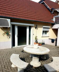 a patio with a table and two benches in front of a house at Appartement proche d'Europa park/Marchés de Noël in Rhinau