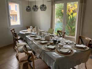 une longue table avec des assiettes et des verres dans l'établissement Maison familiale chaleureuse narbonne, à Narbonne