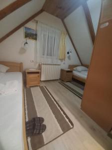 a attic room with a bed and a bedroom with a window at Rooms Skorpijon in Žabljak