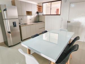 cocina con mesa blanca, sillas y nevera en Apartamento 3 habitaciones Palanoa Rodadero - By Bedviajes, en Santa Marta