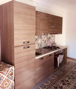 uma cozinha com armários de madeira e um fogão em Casa vacanze Ni Micheli em Naro