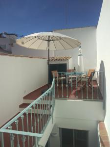 a balcony with a table and an umbrella at Casa 16 in Tavira