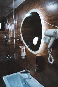 ein Badezimmer mit einem Waschbecken, einem Haartrockner und einem Spiegel in der Unterkunft Cottages LIZA in Kazbegi