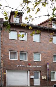 um edifício de tijolos vermelhos com portas de garagem brancas em Gästehaus zum roten Hahn em Lüneburg