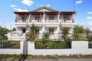 a white house with palm trees in front of it at Bekiri's Studios in Alikanas