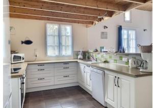 a kitchen with white cabinets and white appliances at l'Echo des Vagues in Foulerot