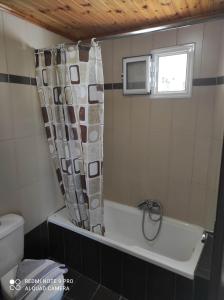 W łazience znajduje się wanna z zasłoną prysznicową. w obiekcie Aglaia House w Korfu