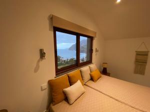 una camera da letto con un letto con una grande finestra di Penha D'Águia Villa a Porto da Cruz