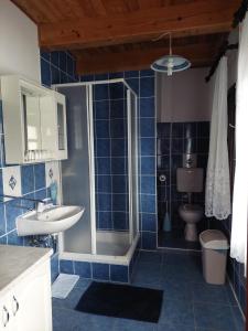 y baño de azulejos azules con ducha y lavamanos. en Sobe Ivan Rastoke 21, en Slunj