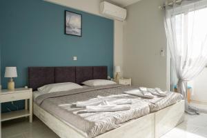 1 dormitorio con 1 cama grande y paredes azules en Amvrosia Apartments en Mastichari