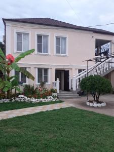a large white house with stairs and a yard at U Asidy Guest House in Gudauta