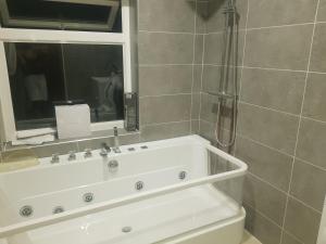 a bathroom with a white tub and a shower at Elegant room In a private House in Rotherham