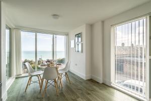 a dining room with a table and chairs and large windows at Seaview West Coast in Bournemouth