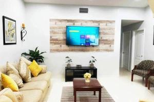 salon z kanapą i telewizorem na ścianie w obiekcie Amazing & cozy Duplex near Zoo Miami ! w Miami