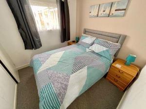 a bedroom with a bed with a quilt on it at The Nest in Hemsby